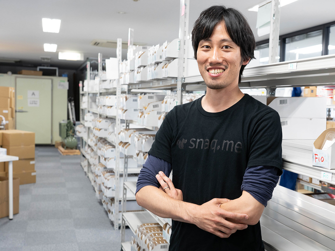 スナックミー代表取締役の服部慎太郎氏。オフィスにはボックスに詰める前のお菓子が並ぶ Photo by Yuhei Iwamoto